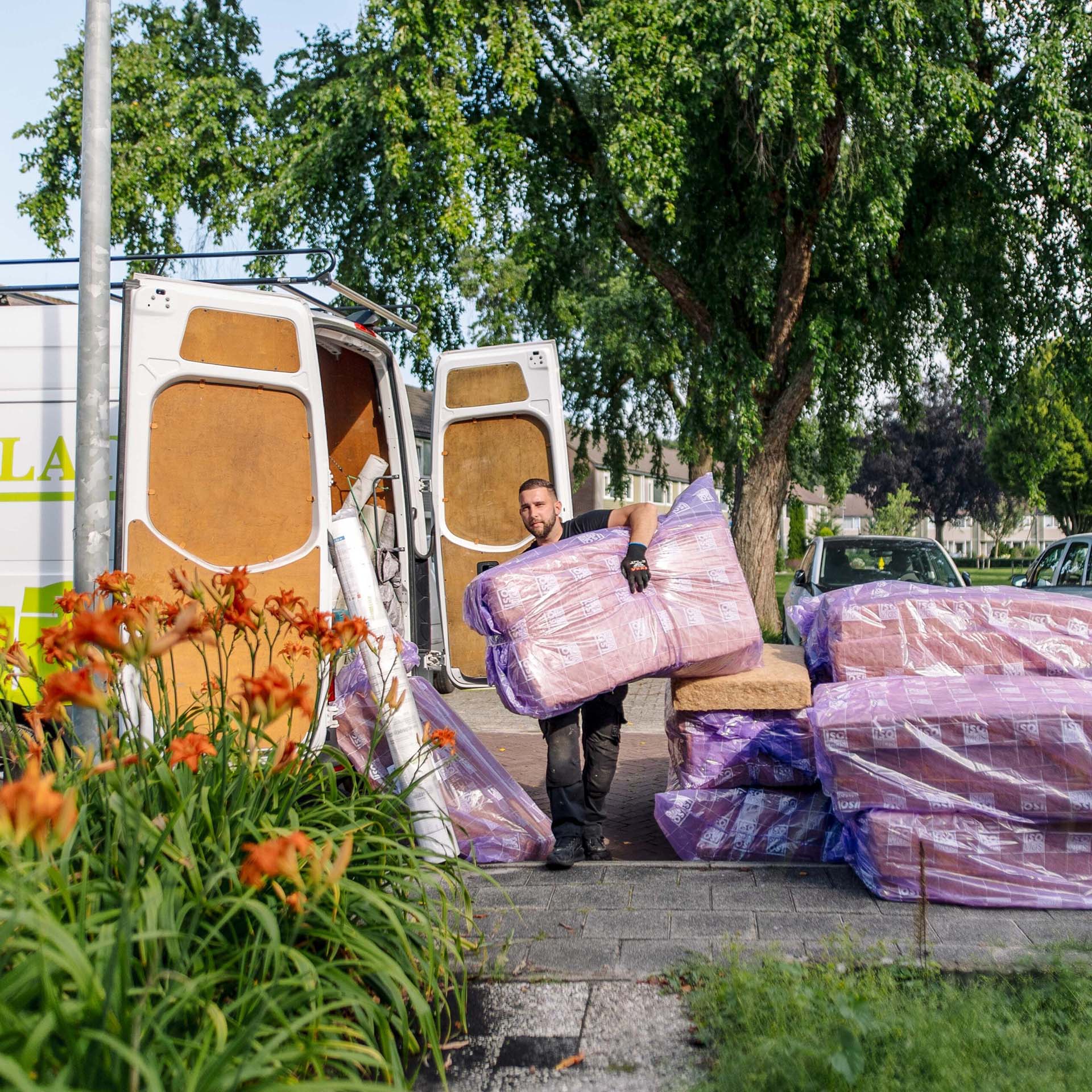 Een lokale vakman laadt isolatiemateriaal uit een bestelbus